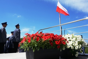 zdjęcie-dzień,biało-czerwona flaga na maszcie, policjanci patrzą w jej kierunku